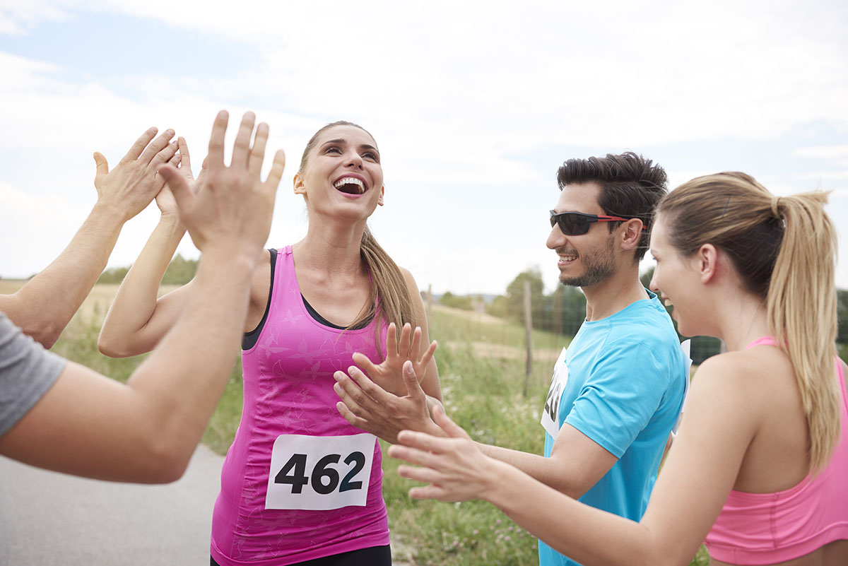 Greeted by the rest of the team Woman running past friends giving high fives