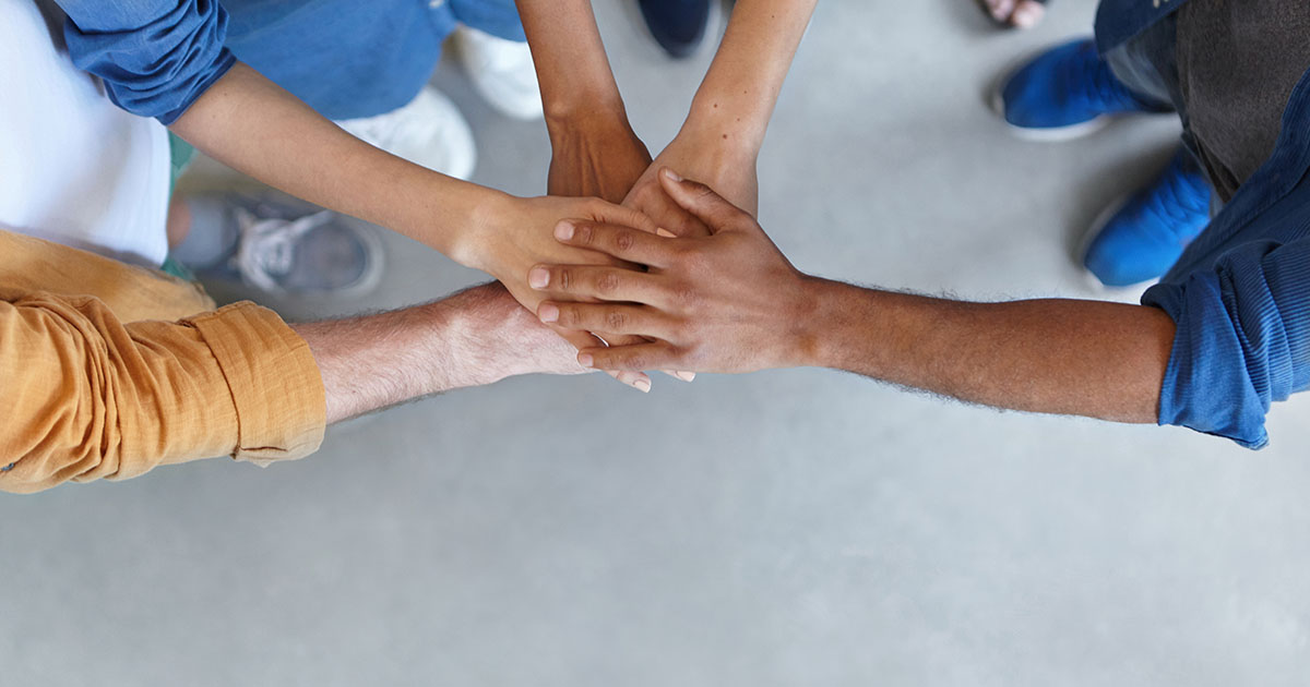 View from above of group of people keeping their hands in pile expressing social friendship, unity, agreement and support. Five people of different sexes collaborating showing their strength Image of hands overlapping together